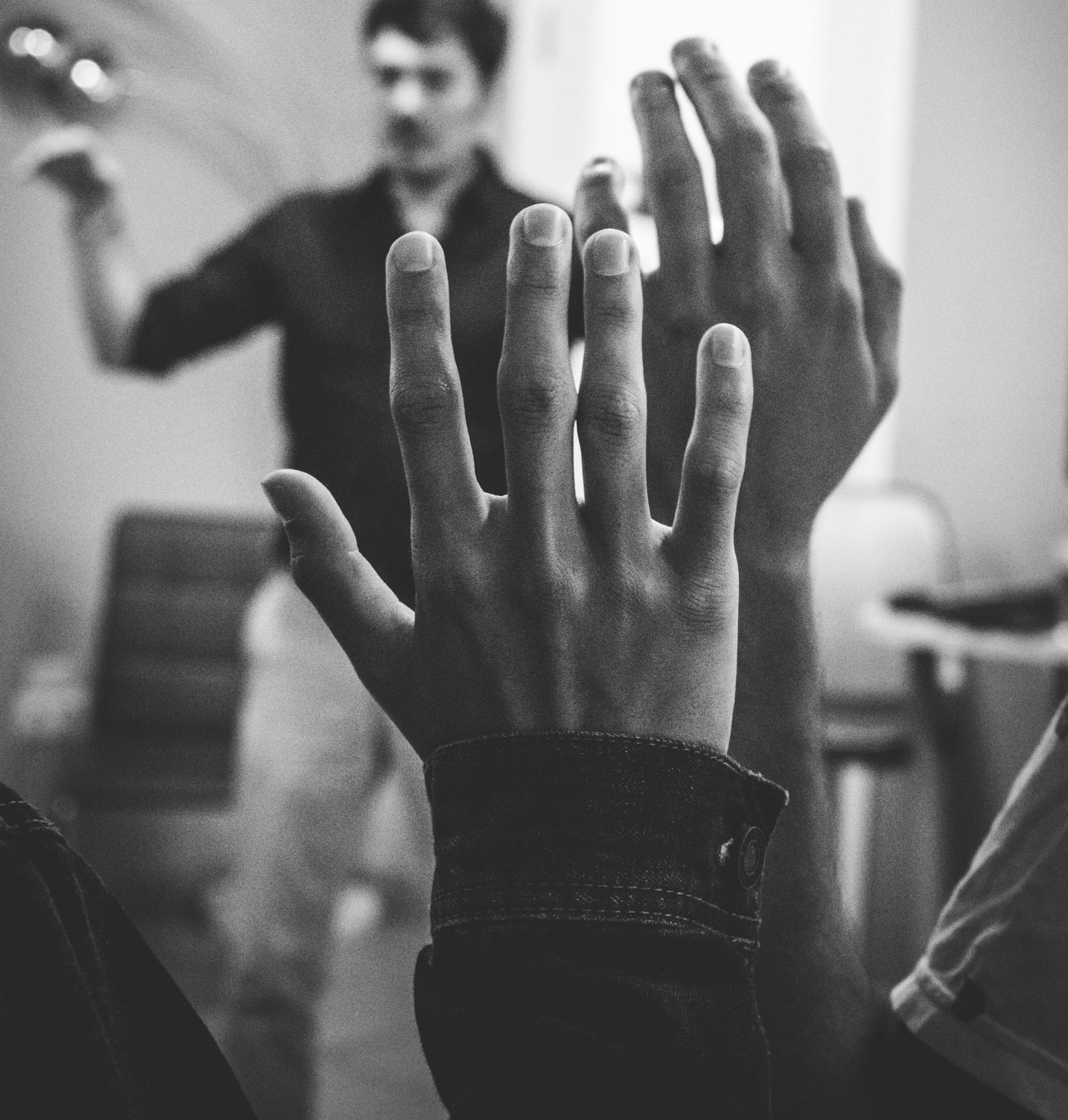 grayscale photography of two people raising their hands